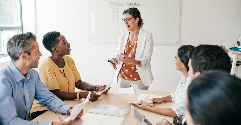 Woman standing in front of a table of coworkers at work