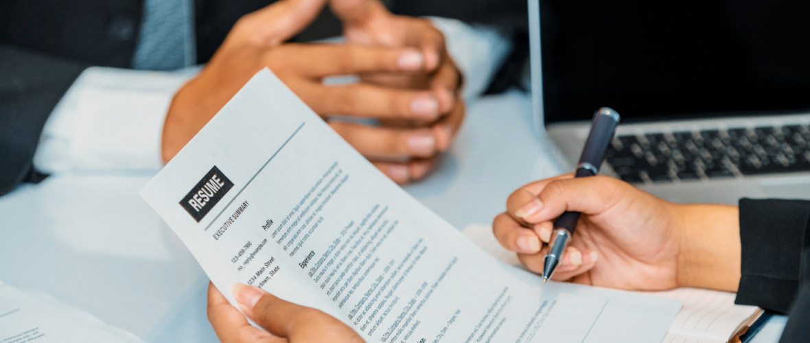Person reviewing a resume and taking notes during an interview.