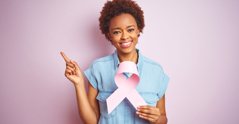 A woman of color holding a pink ribbon