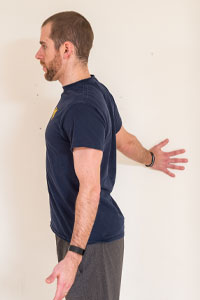 photo of man standing with hand on the wall slightly behind him