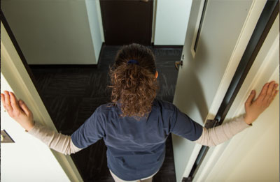 top view of woman standing in doorway with hands on the door frame