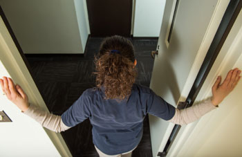 photo of woman standing in a doorway with hands on either side of the opening, view from above