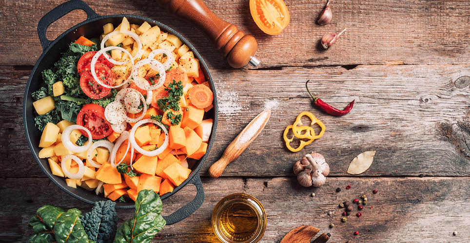 pot full of cut up leafy greens, tomatoes, potatoes and carrots