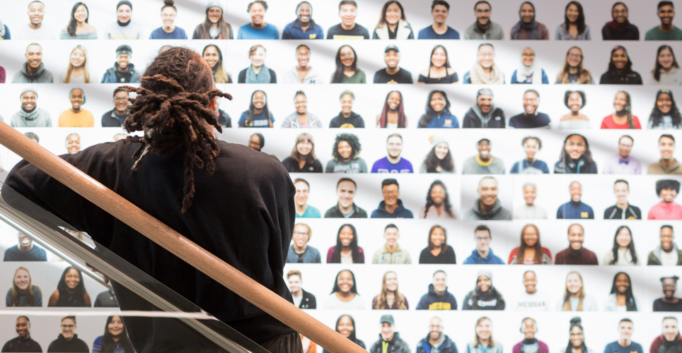 man looking at wall of photos