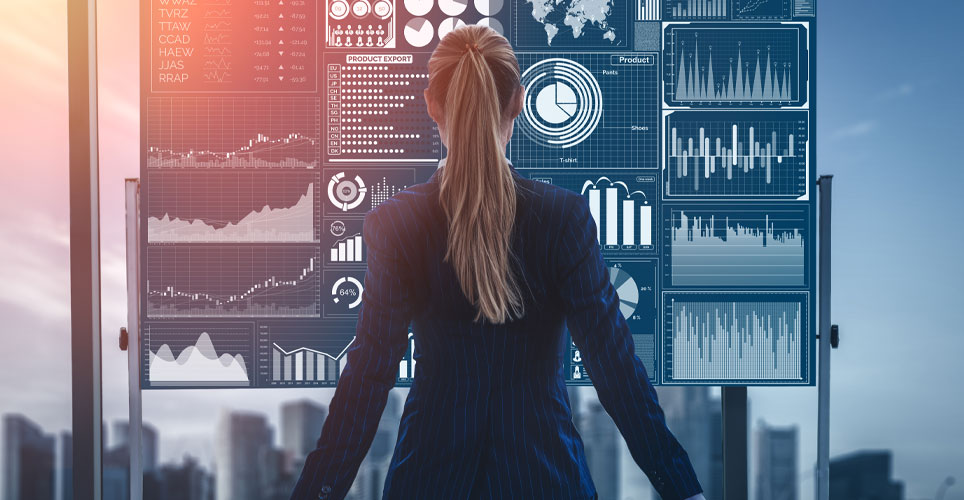 white woman dressed in professional attire with her back to the camera and a data board in her background