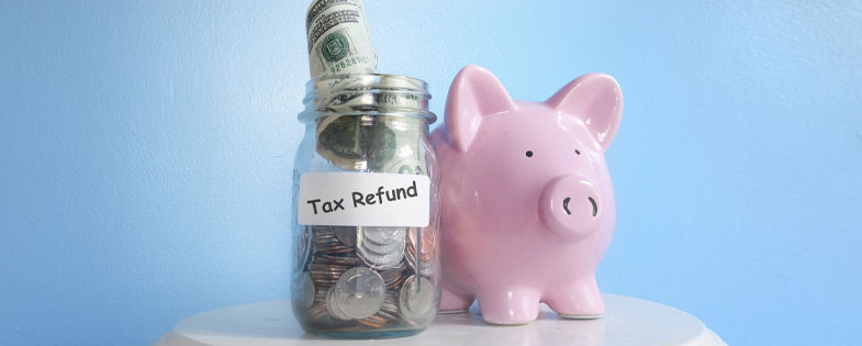 piggy bank next to jar full of money labeled "tax refund" 
