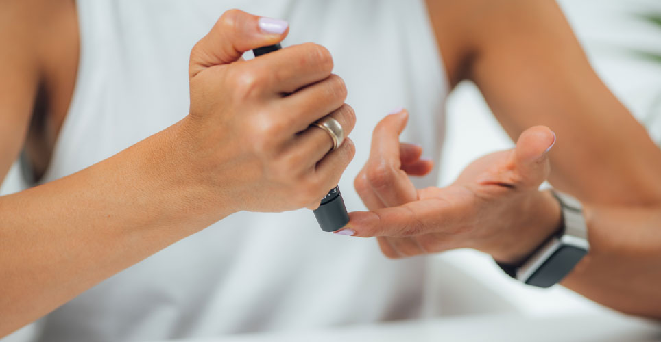 Close up of a woman's hands pricking a finger for a glucose test