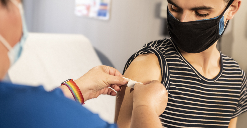 A health care worker putting a bandaid on someone's arm after getting a vaccination
