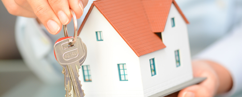 someone holding a miniature house with keys in their other hand