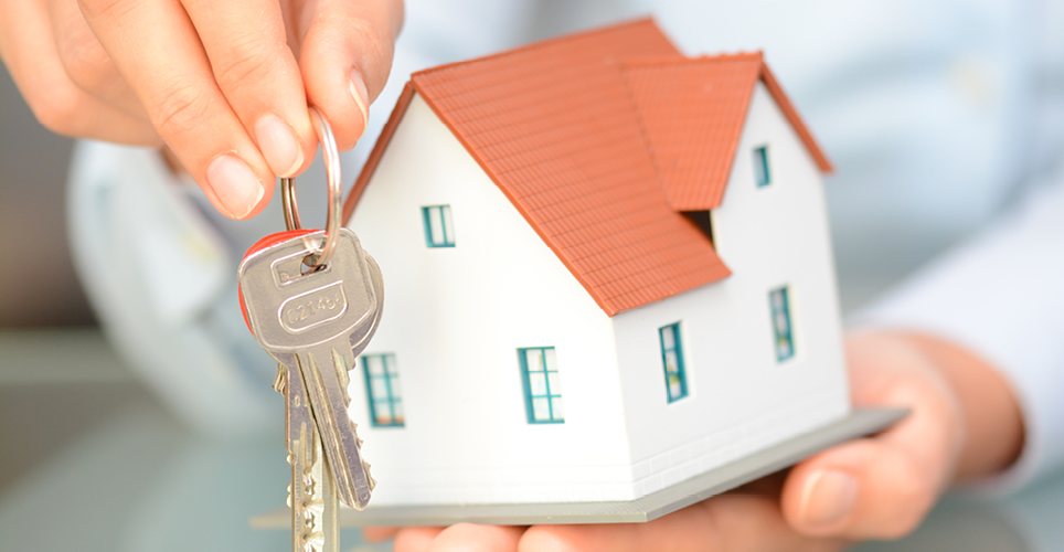 someone holding a miniature house with keys in their other hand
