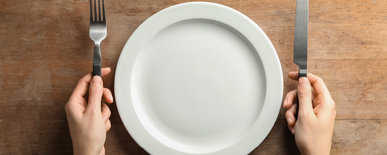 an empty plate with someone holding a fork and knife