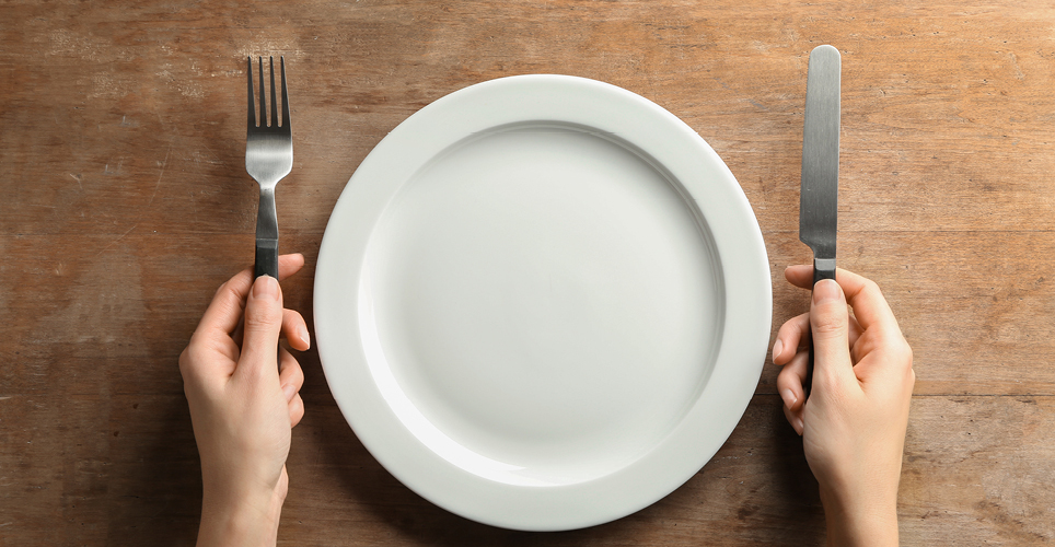 empty plate with someone holding a fork and knife