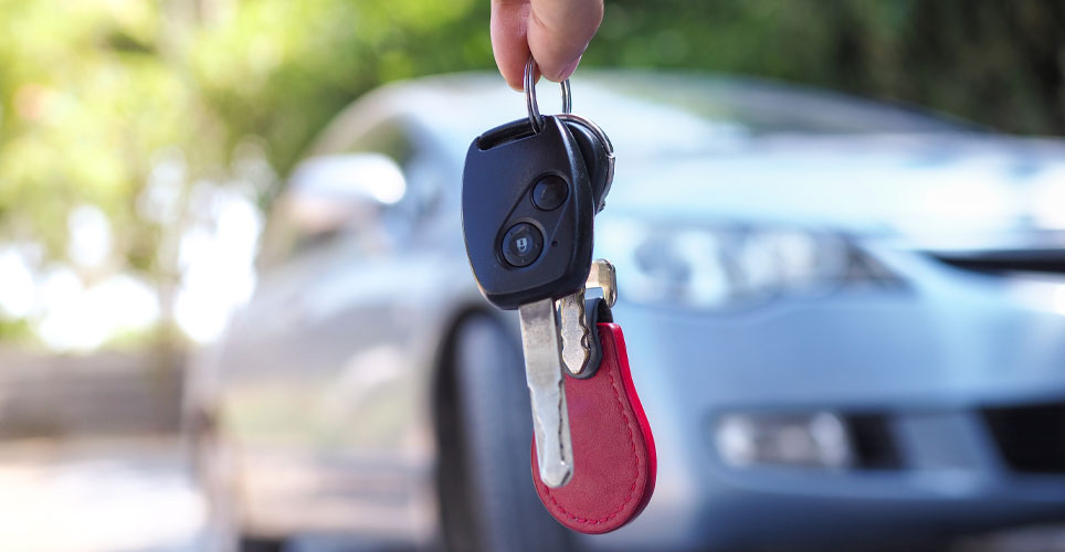 close up of car keys with a silver sedan blurred in the background