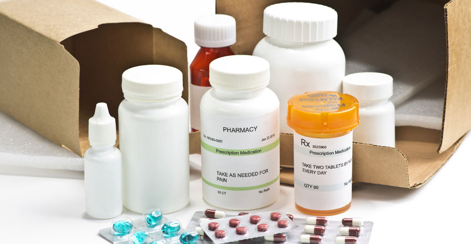 Close up of several prescription medications near two mailing boxes