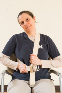 photo of woman sitting with a belt around her neck and side with her head bent to the side