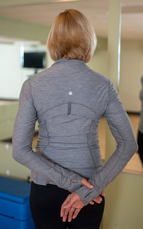 woman standing facing away from camera showing the neck and upper trapezius release start movement
