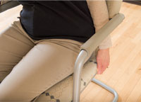 photo of someone sitting focusing on their hands holding the seat of the chair