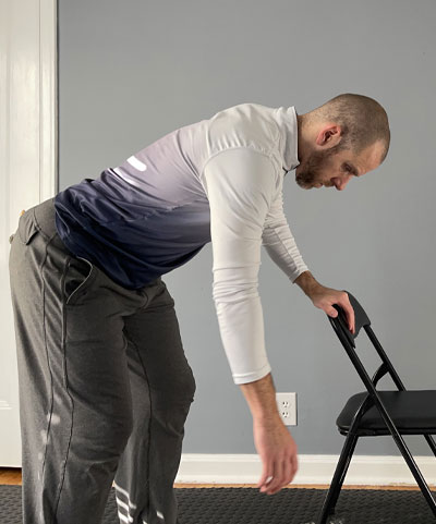 man with one hand on chair leaning over