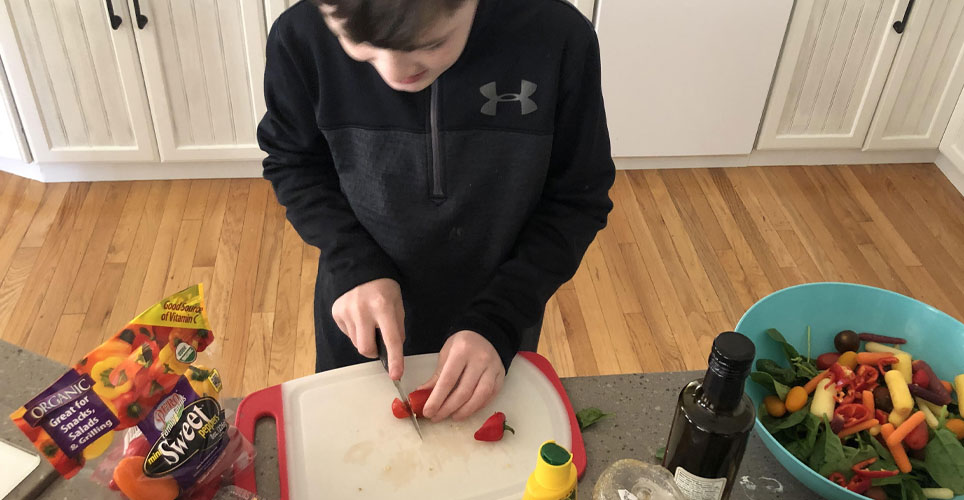 student cutting up vegetables to make a salad