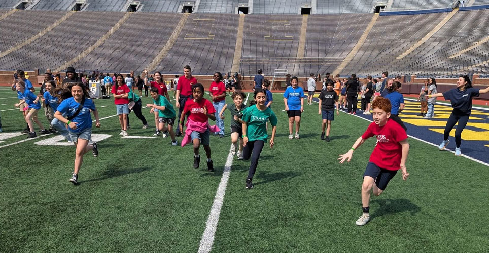 kids running on the field at Michigan Stadium