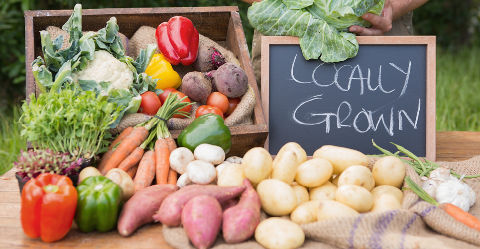 fresh vegetables next to a chalkboard with "locally grown" written on it