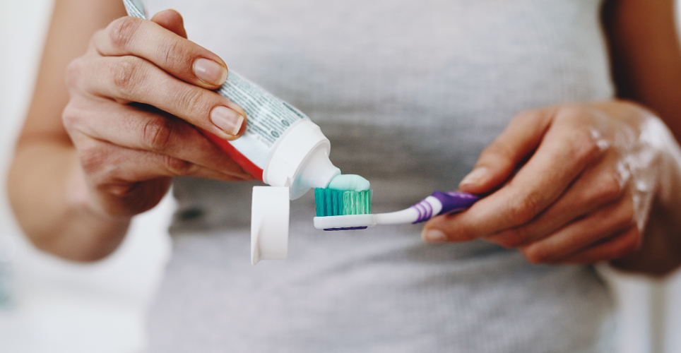 Person putting toothpaste on a toothbrush