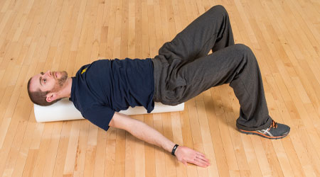 man laying on a foam roller with arms outstretched