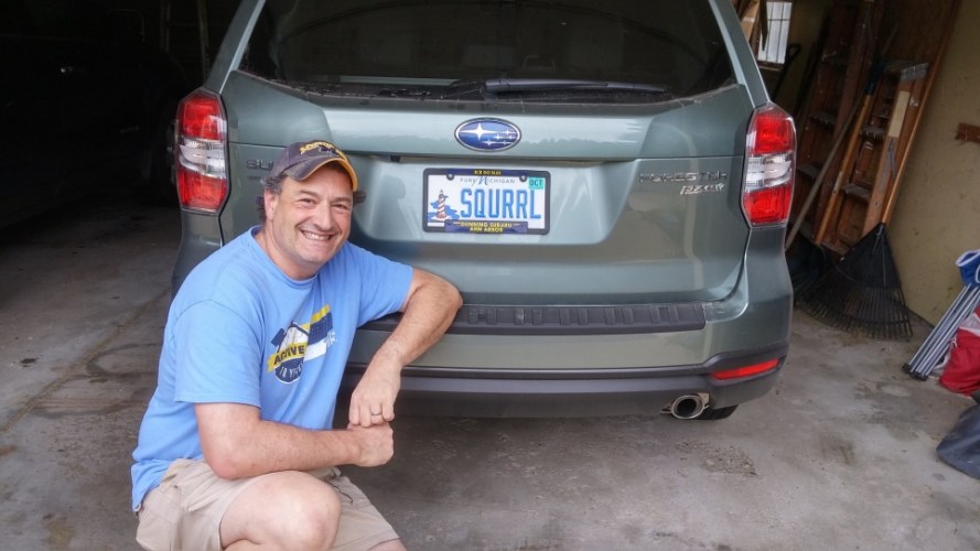 Corey Seeman in front of his car with squirrel license plate