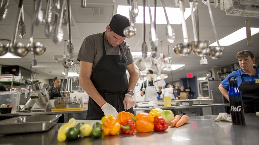 Colton Schick cutting vegetables in a kitchen
