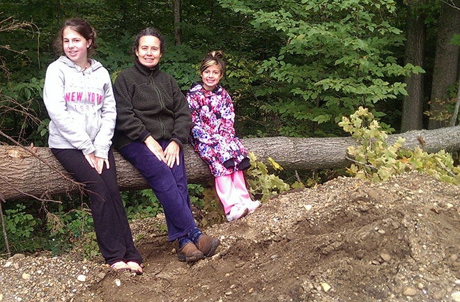 Jan Katz sitting on a log with granddaughters Aurora and Belle