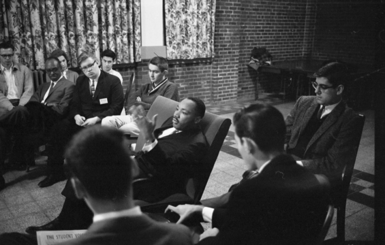 Martin Luther King sitting in a chair talking to a group