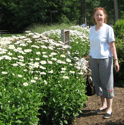 Pene Chevalier standing next to daisies 