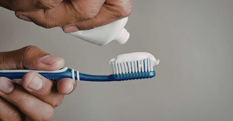 Someone putting toothpaste on a toothbrush