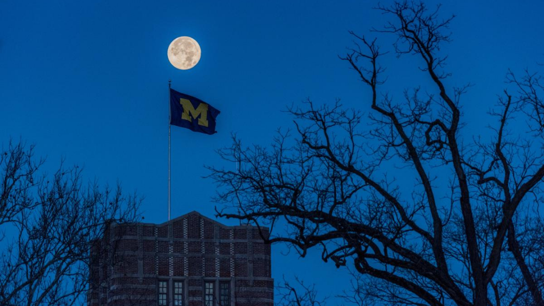 Moonrise above a flag showing the Block M