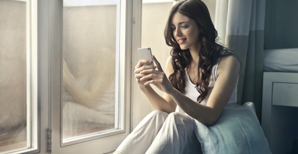woman looking at phone near window.