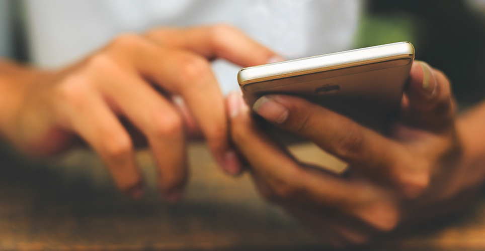 Close up of hands holding a smartphone taping on the screen.