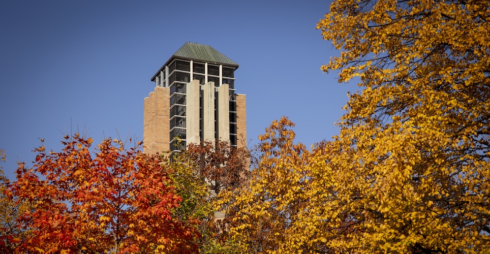 Lurie Bell Tower on North campus, blue sky in the background and trees in the foreground.