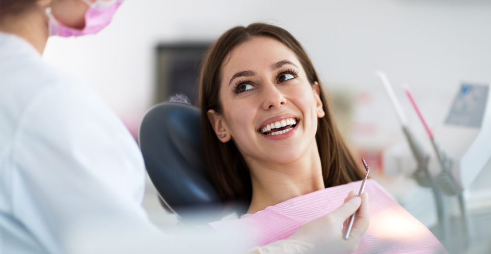 Woman sitting in a dental chair talking to dentist.