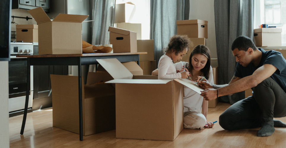 Two parents and a child packing up boxes. 