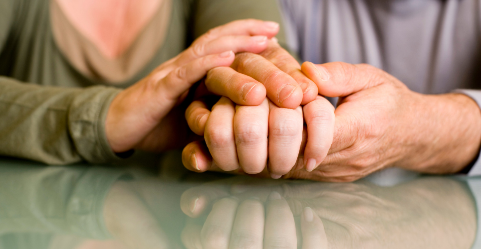 two sets of hands holding each other on a table