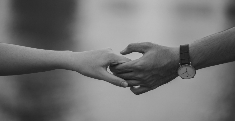 Black and white image of couple holding hands.