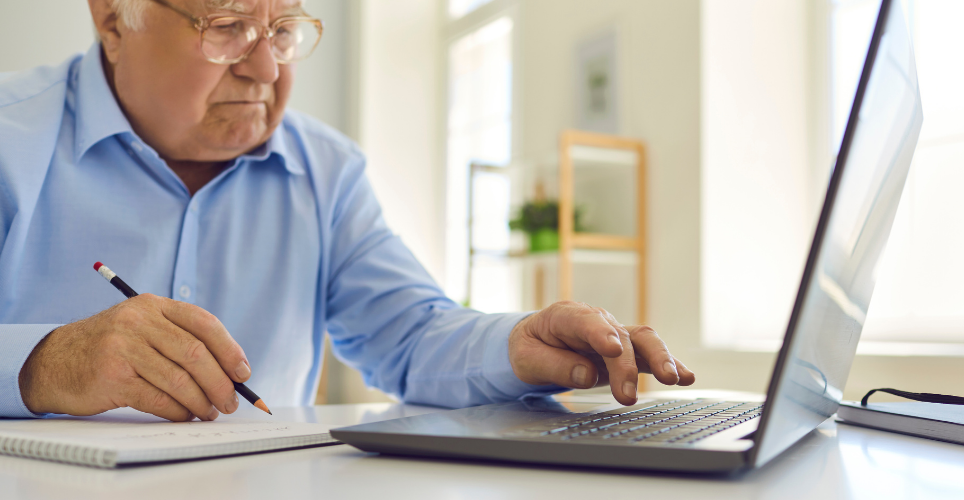 older gentleman at a desk using a lap top