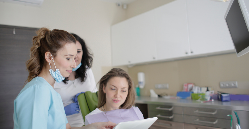 Woman sitting in a chair at the dentist, talking to the dentist. 