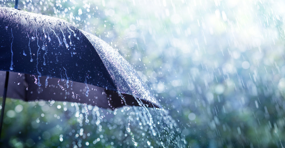 close up of a blue umbrella getting drenched by rain.