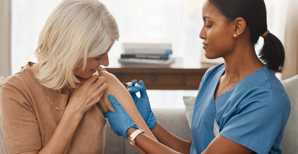 older woman receiving a shot from a female health care worker