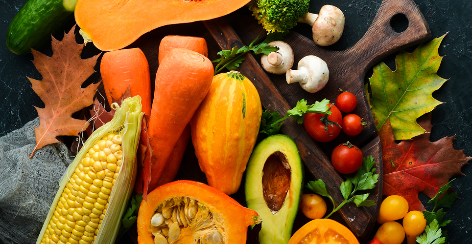 An array of fall squash, corn, mushrooms and other vegetables on a cutting board