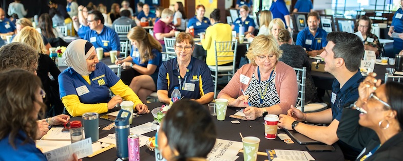 Group of staff sitting at a round table at the Voices annual meeting, laughing and talking