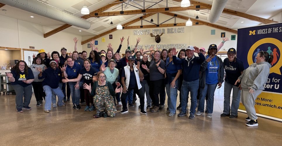 Group of 50 staff volunteers with excited gestures in a large room.