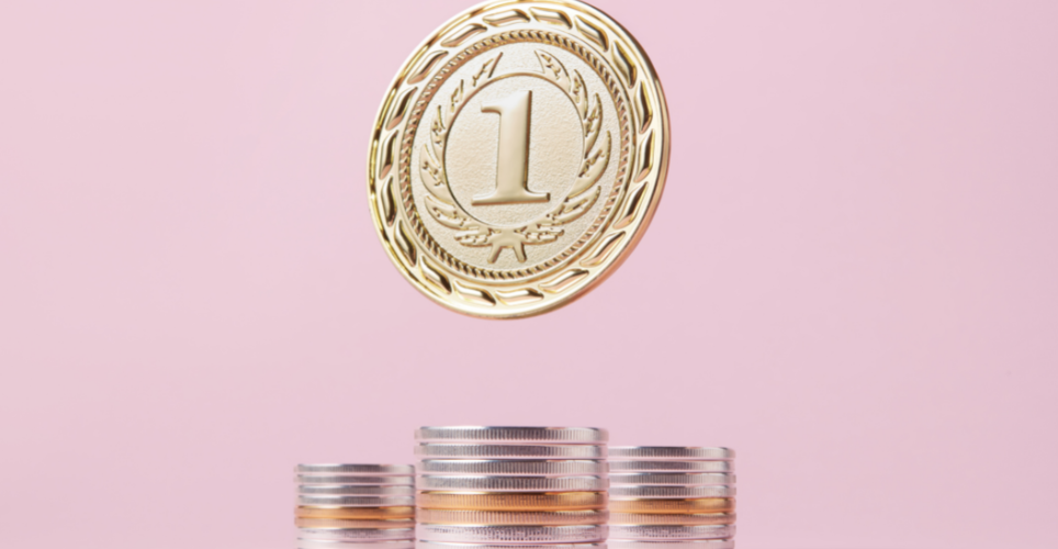 Gold medal with a number one inscribed on it, floating above a stack of coins on a pink background.