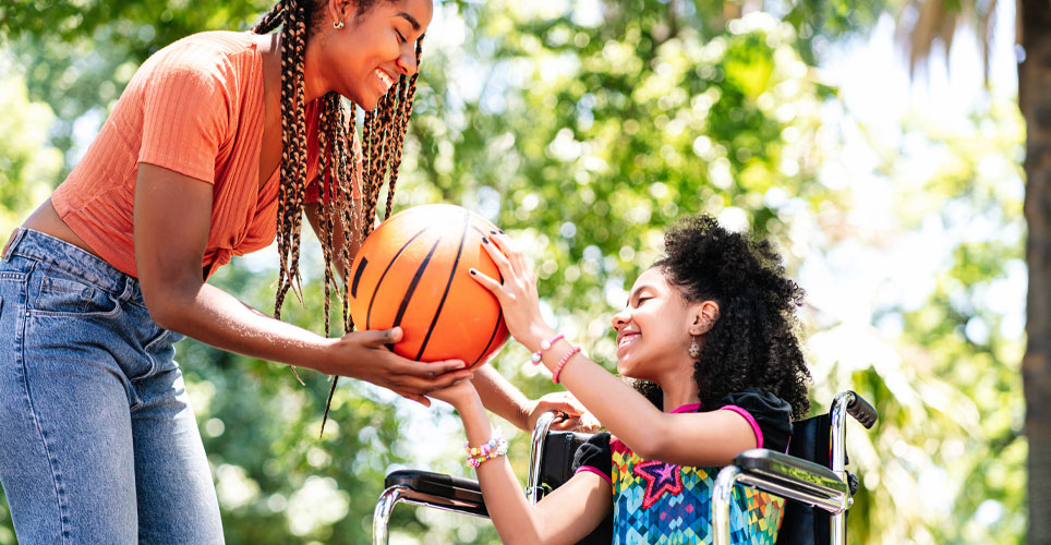 Close of an African-American mom handing a basketball to her daughter who's in a wheelchair